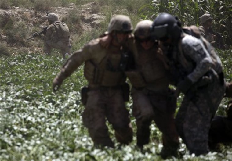 U.S. Marines in the background provide security as a Marine and a U.S. Army Task Force Shadow flight medic, right, rush a Marine wounded in an explosive attack across a field to a medevac helicopter, west of Lashkar Gah, in southern Afghanistan Thursday.
